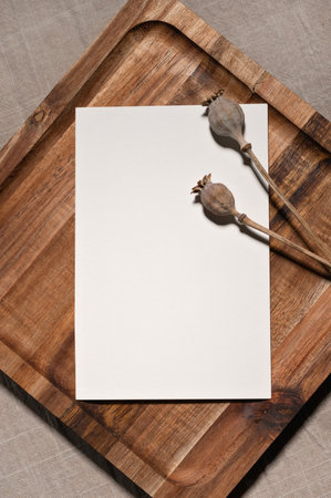 Blank white paper card mockup on wooden brown tray with dried pippy flowers, aesthetic natural background for postcard, invitation or letter design.の写真素材