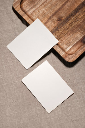Two paper business cards and brown wooden tray on neutral taupe linen tablecloth background, minimal elegant stationery mockup.の写真素材