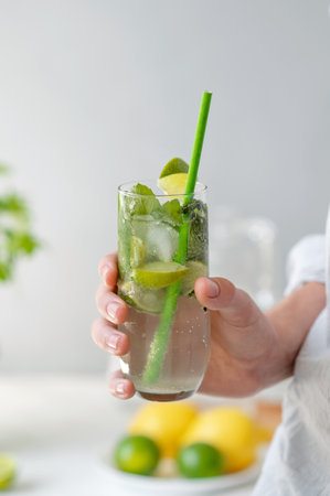 Hand holding glass with mojito cocktail drink, summer refreshing beverage, lifestyle.の写真素材