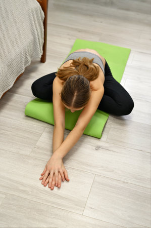 Pilates workout or fitness training in bedroom, authentic wellness and healthy lifestyle concept, young woman do stretching exercises at home.の写真素材