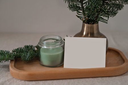 Empty postcard, green candle, plant on wooden tray, aesthetic background with natural light.の写真素材