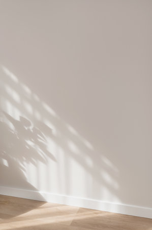 Aesthetic soft sunlight shadows pattern on neutral beige plaster wall and wooden floor background, minimal elegant home design interior detail, backdrop with empty copy spaceの写真素材