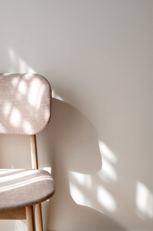 Soft velure and wooden chair with abstract natural sunlight shadows on neutral beige plaster wall background, aesthetic modern home interior detail design conceptの写真素材