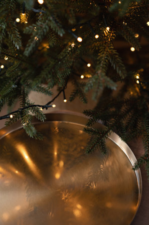 Empty bronze tray near Christmas tree with shining lights bokeh background, aesthetic holiday backdrop with dark mood, vertical template for social media design, copy spaceの写真素材
