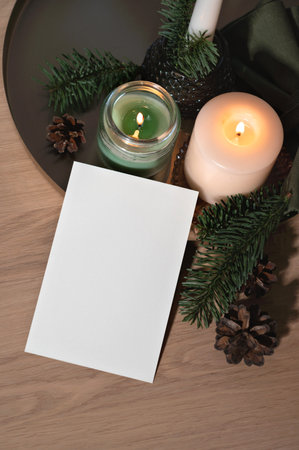 Empty postcard design template, blank paper card mockup, candles and green fir tree branches on tableの写真素材