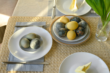 Table decorated for Easter holiday dinner, tabletop with natural dyed yellow, blue gray, green...