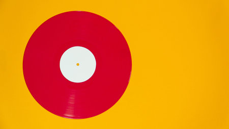Red vinyl record on vibrant background. Clean flat lay retro music concept with copy space.の写真素材