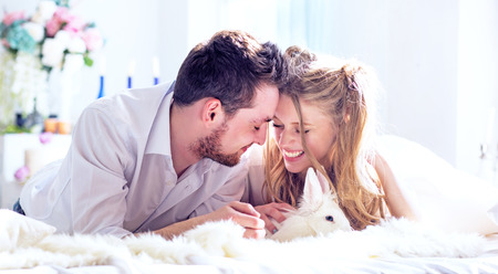The young couple of lovers and a white decorative rabbit celebrates St. Valentine's Dayの写真素材