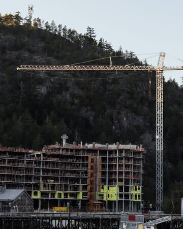 High tower crane at a construction site against the sky.