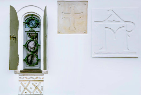 An old window with a wooden frame and metal shutters on a white wall. Patterns on a white wall. Shooting close-upsの写真素材