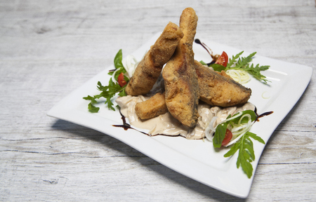 fried fish in creamy sauce with tomatoes onions, arugula and basilの写真素材