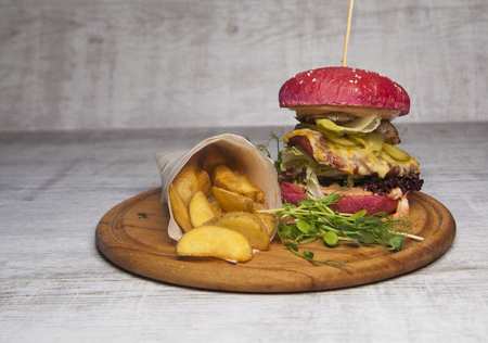 red burger with meat and fried potatoes in pita bread on a wooden tableの写真素材