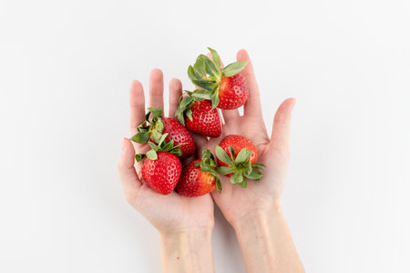 top shot of white photo background there are thin female hands on the palms there are a lot of strawberries only from the garden healthy vitamins seasonal summer fruits vitamin Cの写真素材