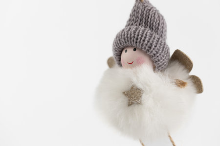 close-up of a hanging textile soft Christmas tree toy in the form of a fluffy round angel in a gray hat, pastel colors, modern decor, legs on stringsの写真素材