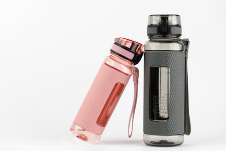 close-up on a white background stands two plastic pink and gray rubberized drinking sports bottle...