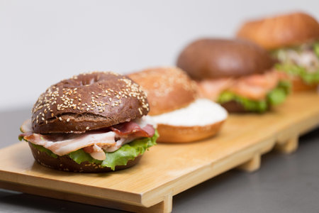 close plan on a white close on wooden there are hardly three bagels filled with red fish and saladの写真素材