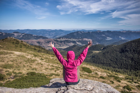 Girl with her hands up on the background of the mountains