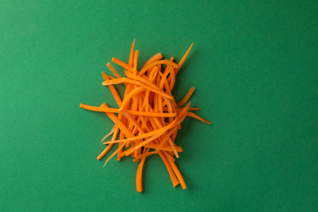 close-up object photography of vegetables on a dark green photo background grated ripe orange carrots into strips for salad or soup fresh vegetables vitamin B healthy lifestyleの写真素材