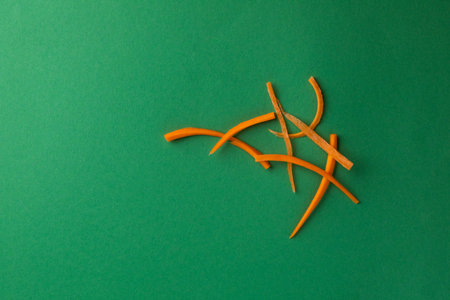 close-up object photography of vegetables on a dark green photo background grated ripe orange carrots into strips for salad or soup fresh vegetables vitamin B healthy lifestyleの写真素材