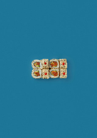 top shot on a blue background lies a set of sushi with rice and seafood avocado sushi wrapped in salmon meat red caviar with seaweed Japanese cuisine kitchen sushi without shadeの写真素材