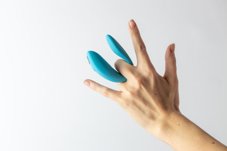 on a white background on women's fingers blue vibrator for double waterproof modern device variety for a couple partner replacementの写真素材