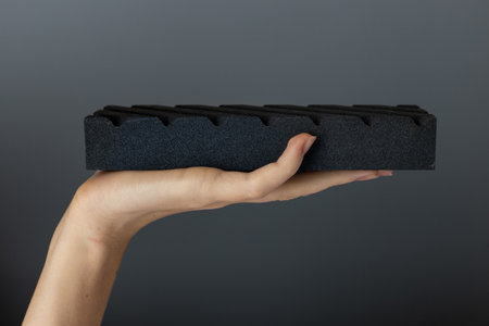 closeup on dark gray background on a woman s palm lies a large abrasive grooved stone on top for sharpening knives and blades, an old methodの写真素材