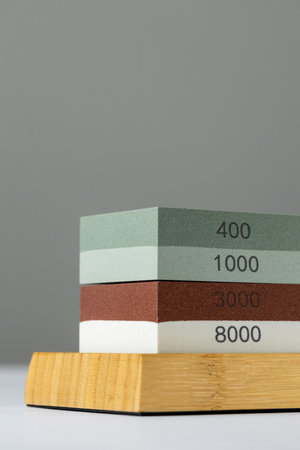 closeup gray background on table lies red and green equipment a set for sharpening and polishing kitchen knives and various blades different abrasiveness of stone retainer for knivesの写真素材