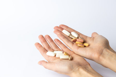 on a white background, on the outstretched palms of female hands, there are pills and vitamins of different shapes and colors.の写真素材