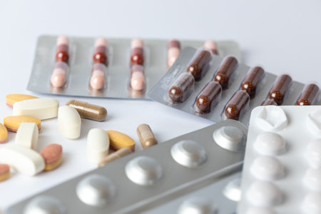 closeup white background on the table there are different silver blisters with colored capsules and tablets health care medical care vitamins on the tableの写真素材