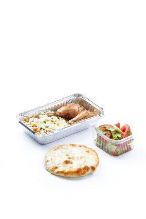 white background disposable plastic and foil tableware food snack steamed rice with vegetables with chicken leg with freshly chopped vegetables and bread flatbreadの写真素材