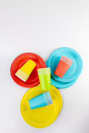 top shot on white background there are three paper cups yellow red and blue with matching paper plates set disposable tableware standard picnic setの写真素材