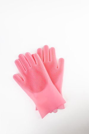 On white background lie large thick rubber pink gloves with texture for easy dish washing replacement sponge for dishes care of hands protection from chemicalsの写真素材