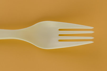 close up soft yellow background pair of plastic white forks disposable tableware reusable care for the planet picnic setの写真素材