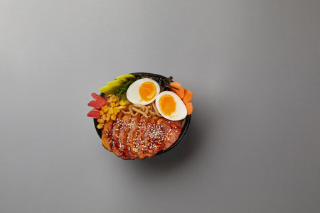 top shot on gray background professional kitchen soup black plate with classic ramen with pork boiled eggs nori sheet corn egg noodles Japanese traditional cuisineの写真素材