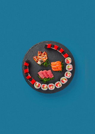 patterned sushi and sashimi on a blue background on a black plate cooking traditional decor a lot of seafoodの写真素材