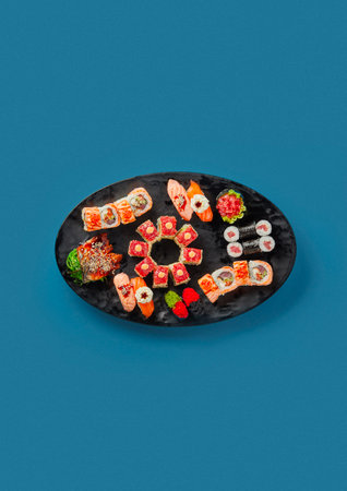 patterned sushi and sashimi on a blue background on a black plate traditional decor a lot of seafoodの写真素材