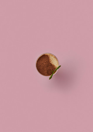 top shot on pink background glass with vanilla pudding decorated with cocoa powder garnished with a mint leafの写真素材