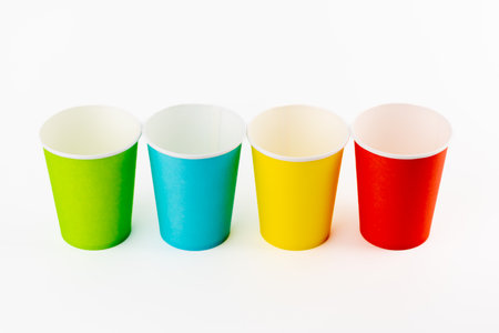 top shot white background, four paper cups for coffee and tea painted in red, green, yellow and blue, disposable tableware, attributes for trips, recreation and picnics, eco cups, waterproofの写真素材