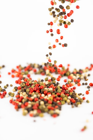 on white background a pile of mixed large aromatic peppers black red and white the main seasoning for food peppercorns indian and european spices spill from the topの写真素材