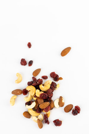 top shot on white background a pile of different kinds of nuts is poured healthy food lots of amino acids and antioxidants omega healthy fats in nuts almond pit cashew walnut red cranberryの写真素材