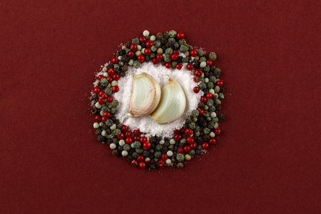A Creative Arrangement of Garlic Cloves Surrounded by Colorful Peppercorns and Sea Salt on a Rich...