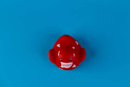 A Vibrant Red Rubber Duck with Heart Patterns on a Bright Blue Background, Ideal for Fun Bath Time Activities and Cheerful Decor.の写真素材
