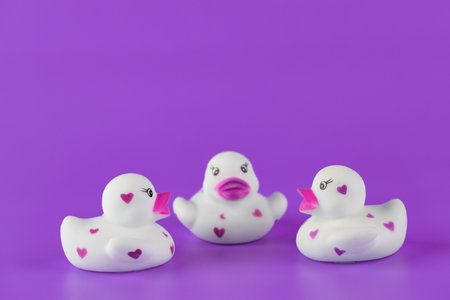 Adorable Collection of Three Cute Rubber Ducks Displaying Hearts Against a Vibrant Purple Background for a Fun and Playful Vibe Perfect for Children s Toysの写真素材