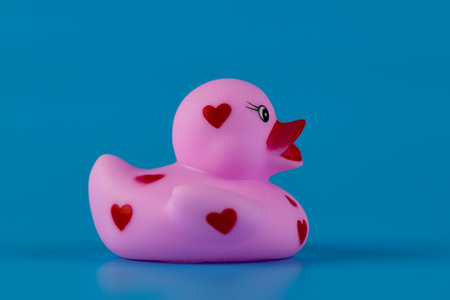 Charming Pink Rubber Duck with Heart Patterns Impeccably Displayed Against a Bright Blue Background Captivating the Imagination of Kids and Adults Alikeの写真素材