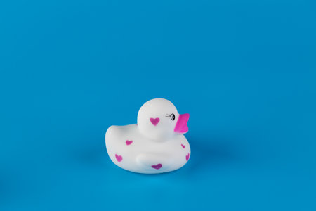 Adorable White Rubber Duck with Pink Hearts Set Against a Bright Blue Background, Perfect for Cute Decor or Bath Time Funの写真素材