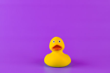 A Cheerful Yellow Rubber Duck Glossy Brightly Colored Against a Light Purple Background Evoking Nostalgia and Joy Associated with Bath Time and Fun in the Waterの写真素材