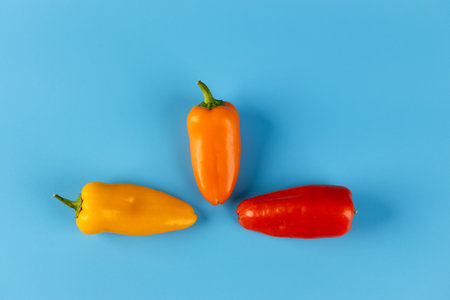 Colorful Bell Peppers on a Bright Blue Background, Perfect for Culinary Presentations or Vibrant Food Photography Sessions to Inspire Healthy Eating and Recipesの写真素材