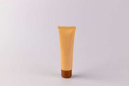 A Trendy Cosmetic Tube in a Soft Yellow Shade with a Brown Bottom, Perfect for Storing Beauty Products and Enhancing Daily Makeup Routines and Glam Looks with Convenienceの写真素材
