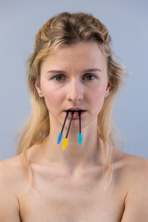 A Unique Portrait Featuring a Model with Colorful Mascara Wands in Her Mouth, Exploring Themes of Beauty and Self-Expression, Captured in an Artistic and Provocative Mannerの写真素材