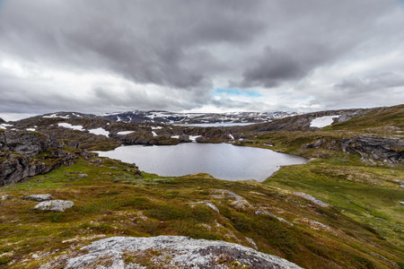 Majestic Scenic Landscape Featuring a Serene Lake Surrounded by Lush Greenery and Snow-Capped...